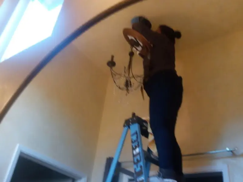 Electrician installing a chandelier in a Mountain Park residence